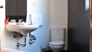 A modern bathroom with a white sink, toilet, and bathtub. - Pensión Residencia Buenos Aires (Vigo)