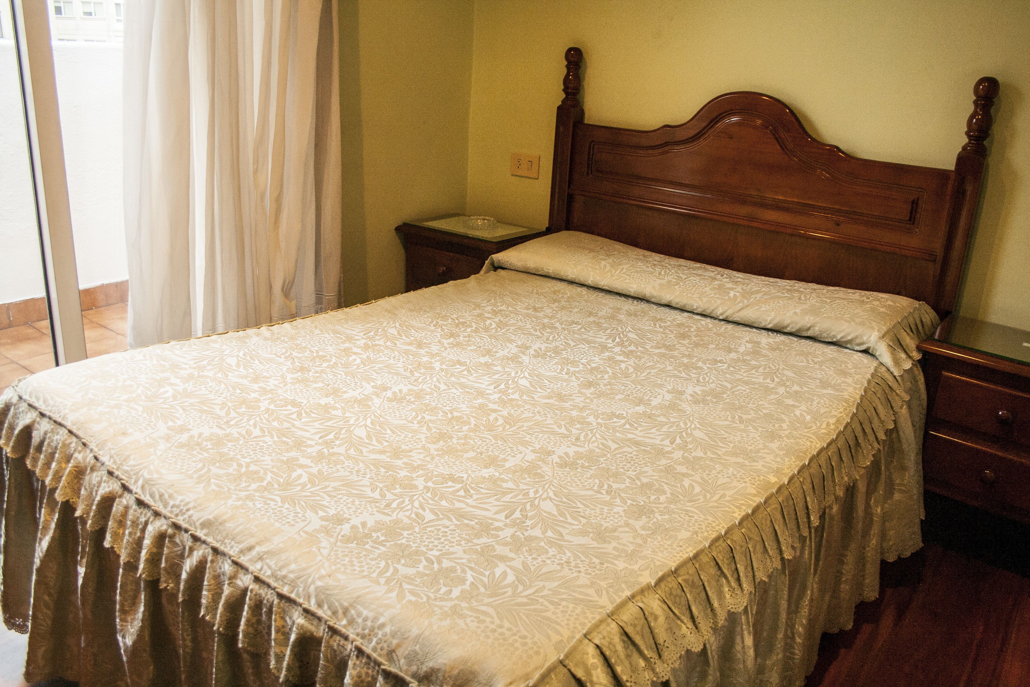 Un dormitorio con una cama de madera, una mesita de noche y una mesita auxiliar.
