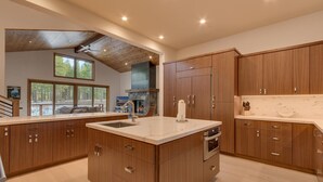 Una cocina moderna con armarios de madera, una isla central con un lavamanos y una chimenea de piedra.