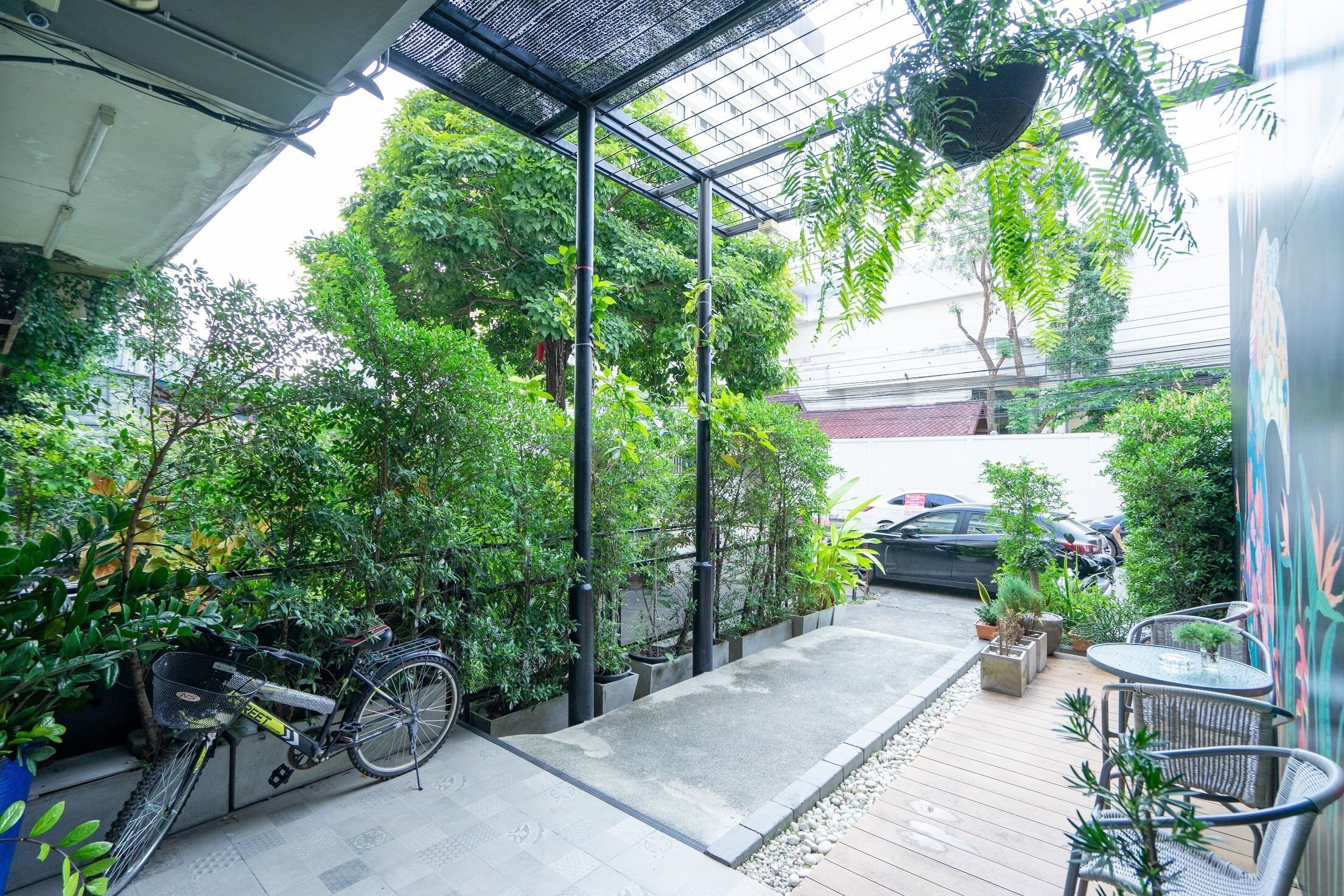 Un espacio al aire libre techado con una bicicleta, plantas en macetas y una zona de estar.