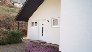 A white building with a brown roof, a door, and two windows. - Ferienhaus am Stausee Bitburg (Biersdorf am See)