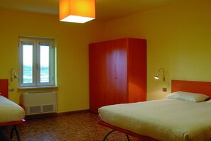 Une chambre d’hôtel avec deux lits, une fenêtre, une armoire et un radiateur.
