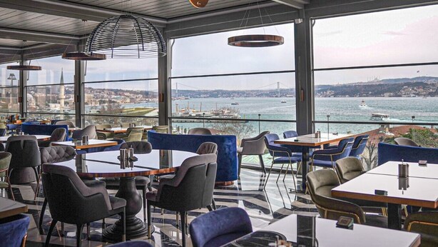 A restaurant with tables and chairs, large windows with a view of a bridge and water. - Metropolitan Hotels Bosphorus (Istanbul)