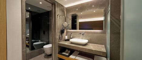 A modern bathroom with a vanity, mirror, and a toilet.