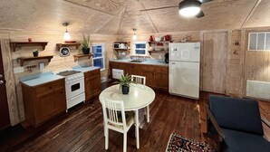 Una cocina compacta con armarios de madera, una estufa blanca y una mesa de comedor con sillas.