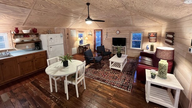 Un interior acogedor con paneles de madera, zona de comedor, cocina y espacio para sentarse.