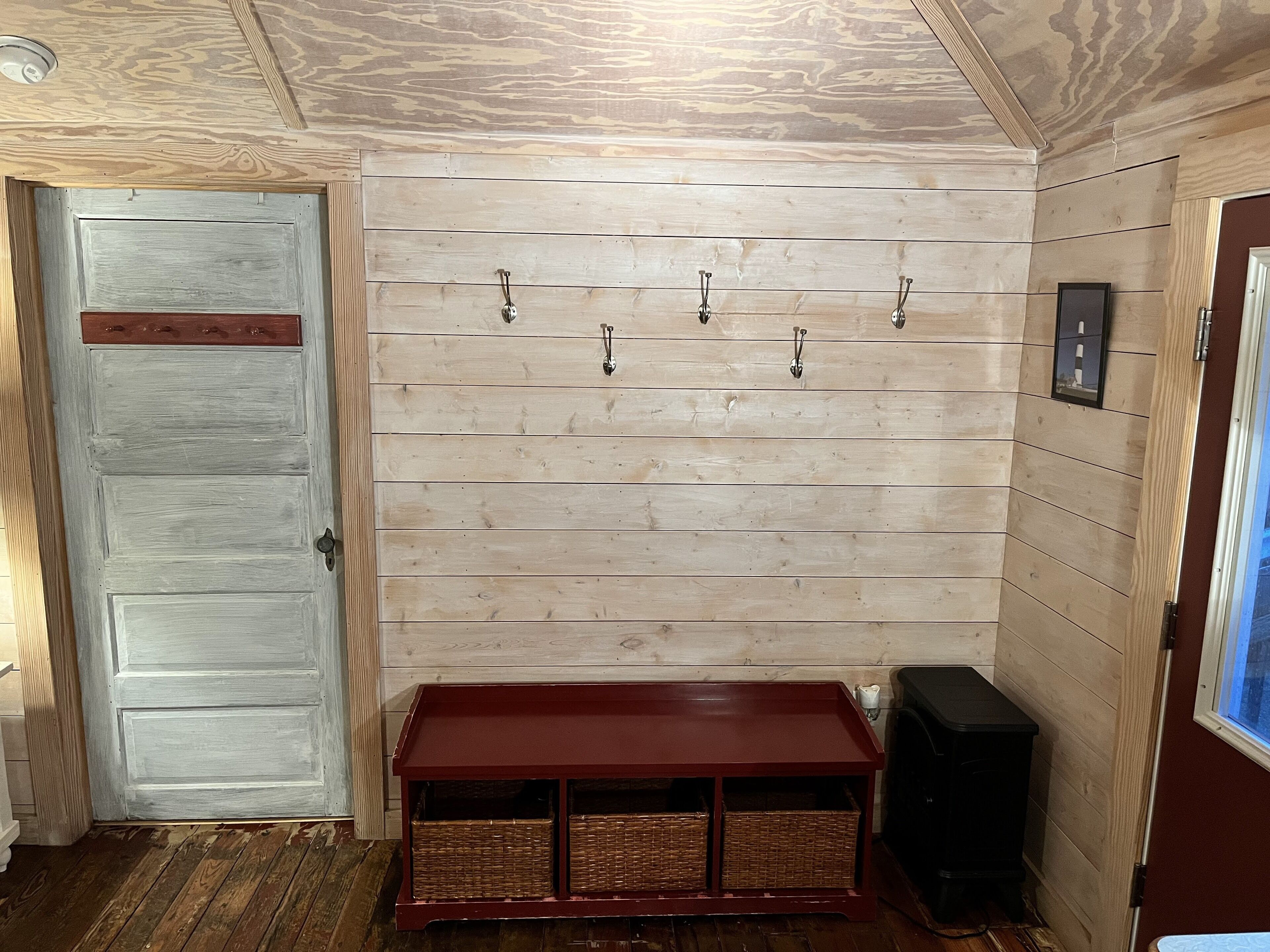 A room with a wooden wall, a door, a bench, and a speaker.