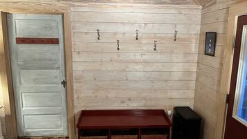 A room with a wooden wall, a door, a bench, and a speaker.
