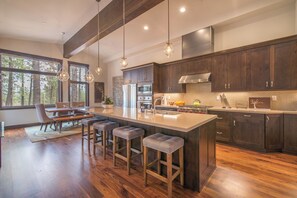 A modern kitchen with dark wood cabinets, stainless steel appliances, and a large island with bar stools. - Alpine Sierra at Schaffer's Mill, Club Amenities Ski & Golf, Lake Tahoe! (Truckee)