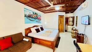 A hotel room with a bed, a wooden ceiling, a painting of a riverside scene, a television, and a desk with a chair. - Veivaag Lodge (Sekondi-Takoradi)