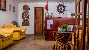 A reception area with a wooden desk, a map, and a flag. - Veivaag Lodge (Sekondi-Takoradi)