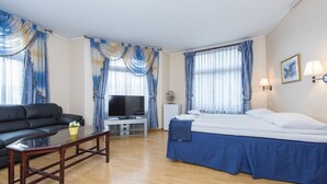 A hotel room with a bed, a sofa, a TV, a desk, and a lamp. - Stavanger Lille Hotel (Stavanger)