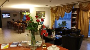 A hotel lobby with a dining area, a reception desk, and a bookshelf. - Stavanger Lille Hotel (Stavanger)