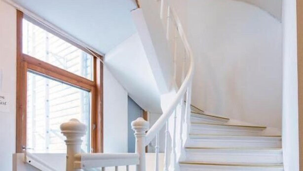A staircase with white balusters and a wooden handrail, leading to a landing with a window. - Stavanger Lille Hotel (Stavanger)