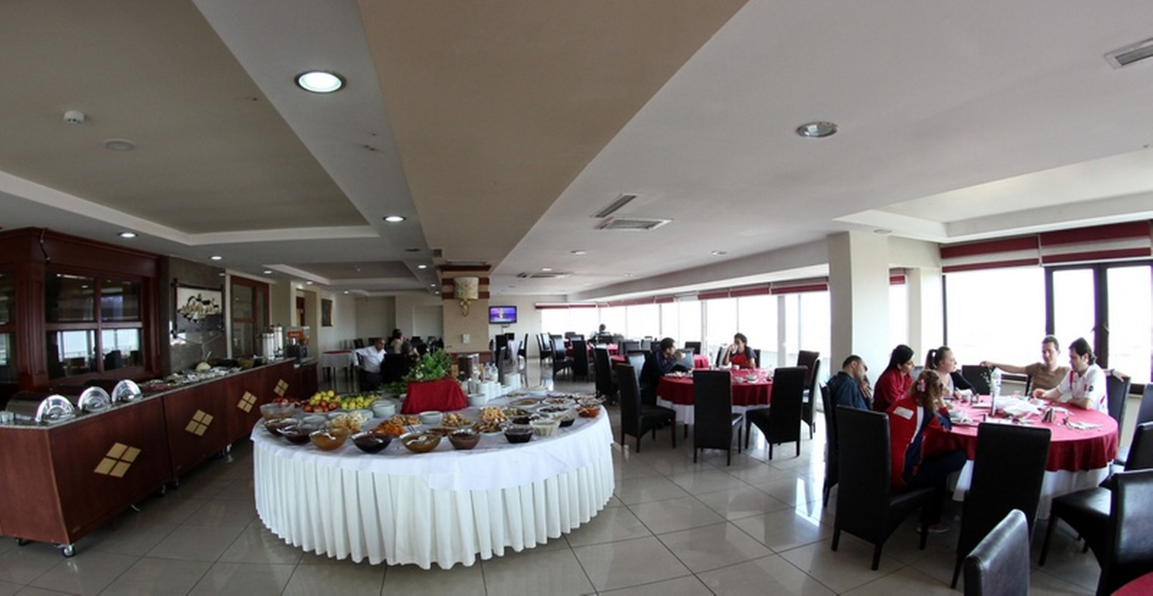 A buffet area with a variety of food items, a central serving station, and several dining tables with chairs.
