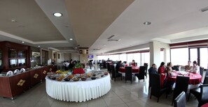 A buffet area with a variety of food items, a central serving station, and several dining tables with chairs. - Grand Ozeren Otel & Spa (Burdur)
