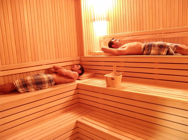 A sauna with wooden benches and a small wooden bucket.