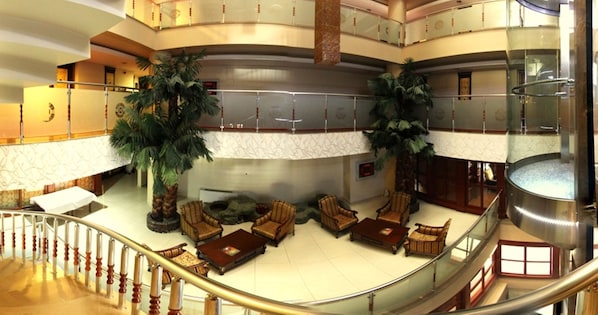 A multi-level hotel lobby with a central seating area, a staircase, and a glass railing. - Grand Ozeren Otel & Spa (Burdur)