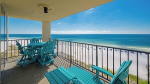A balcony with turquoise Adirondack chairs and a view of the beach. - *TOP GUEST CHOICE* Premium Two Bedroom @ Phoenix II (Orange Beach)