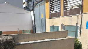 A concrete structure with a metal railing, surrounded by potted plants and a tiled floor.