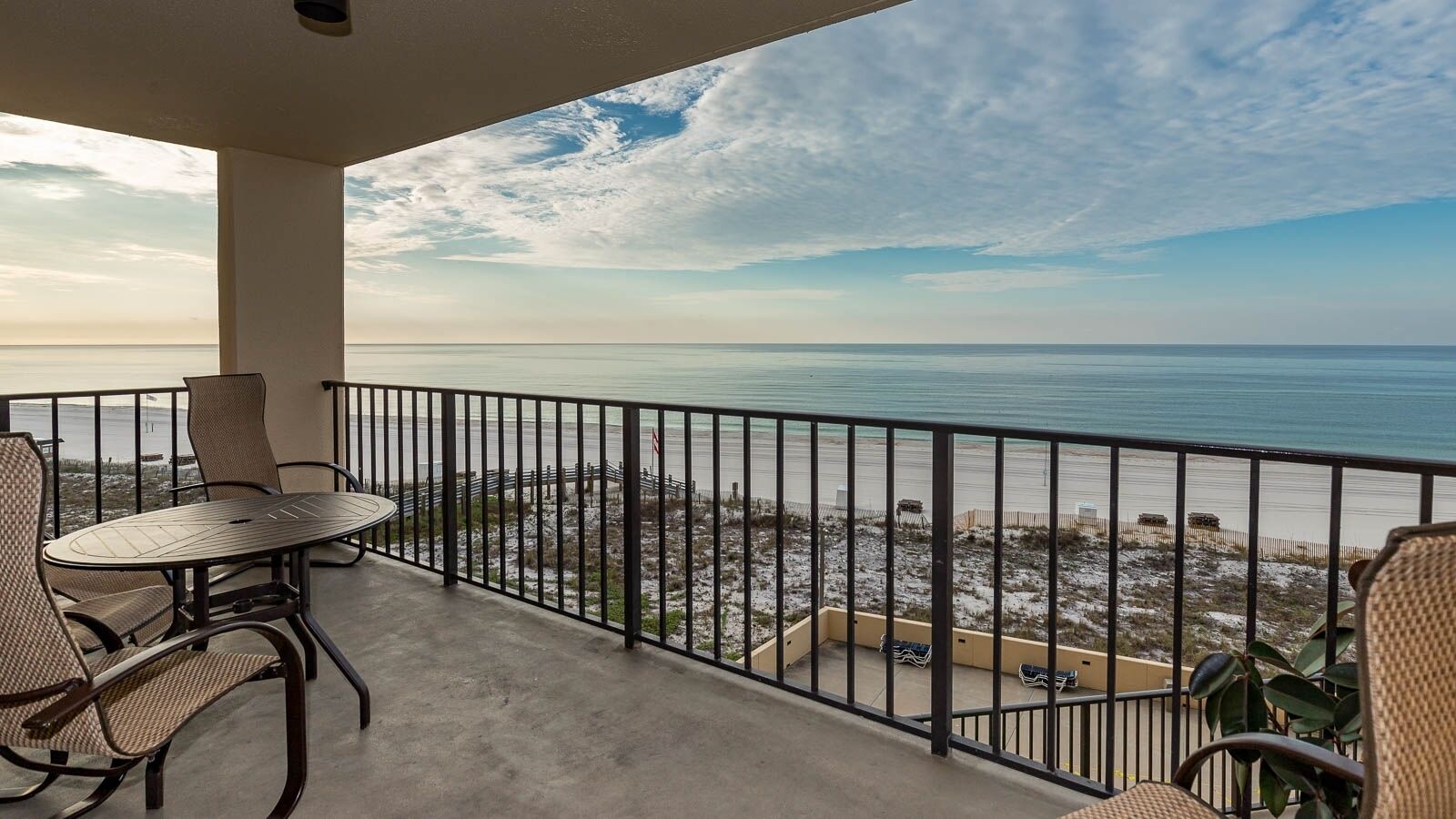 A balcony with a view of the beach and ocean.