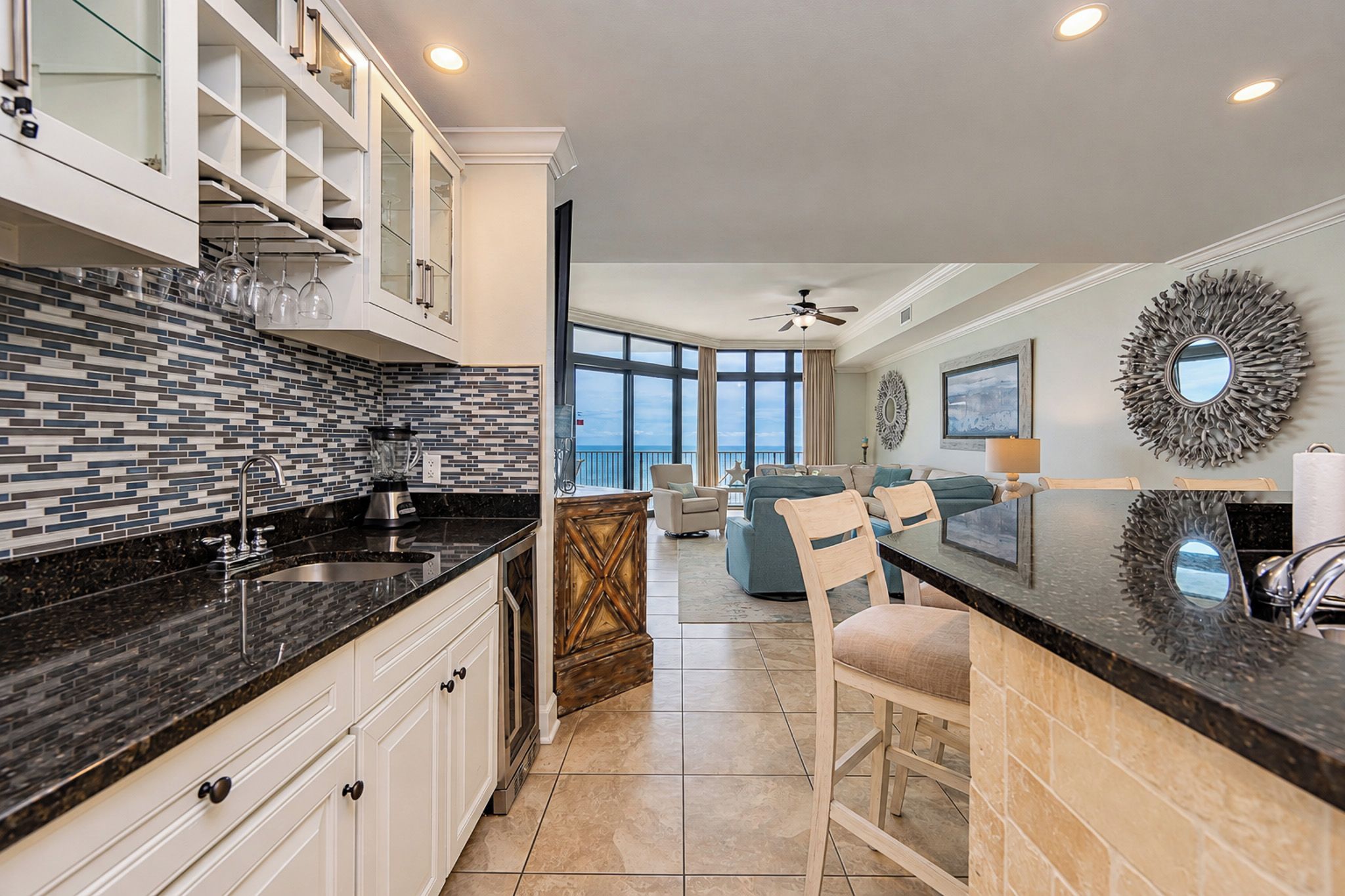 A modern kitchen with a black countertop, white cabinets, and a large window.