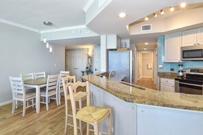 A modern kitchen with a granite countertop, white cabinetry, and a built-in microwave. - Hardwood flooring throughout updated, tropical condo! 🌺 (Destin)