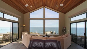 A spacious living area with a large window offering a view of the ocean. - Private, Oceanfront Views, Starlink WiFi, Timber Cove (Jenner)