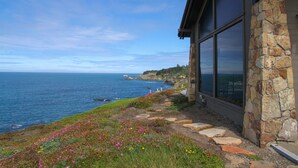 A coastal building with stone walls and large windows overlooking the ocean. - Private, Oceanfront Views, Starlink WiFi, Timber Cove (Jenner)