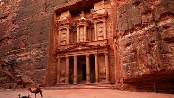 A carved rock facade with columns and a central doorway, typical of ancient architecture.