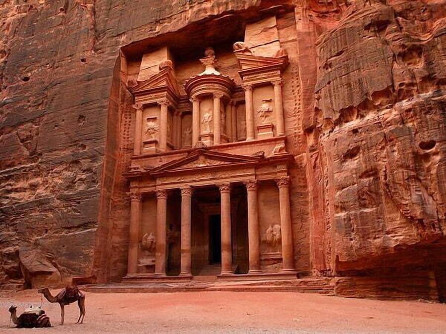 A carved rock facade with columns and a central doorway, typical of ancient architecture.