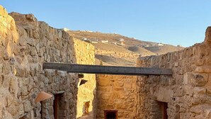 A stone-walled courtyard with a tiled floor and a wooden beam overhead. - Hayat Zaman Hotel & Resort (At-Taybeh)