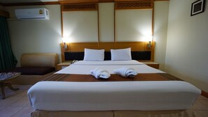 Camera d'albergo con un letto grande, due comodini, una sedia e un condizionatore d'aria a parete.