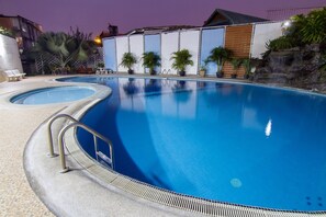 A swimming pool with a clear blue water surface, surrounded by lounge chairs and potted plants. - Supanich Railway Station (Chiang Mai)