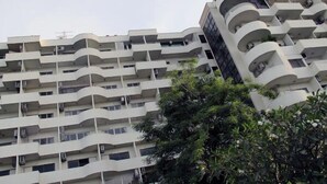 Un edificio residenziale a più piani con balconi, condizionatori d'aria e un albero sullo sfondo.