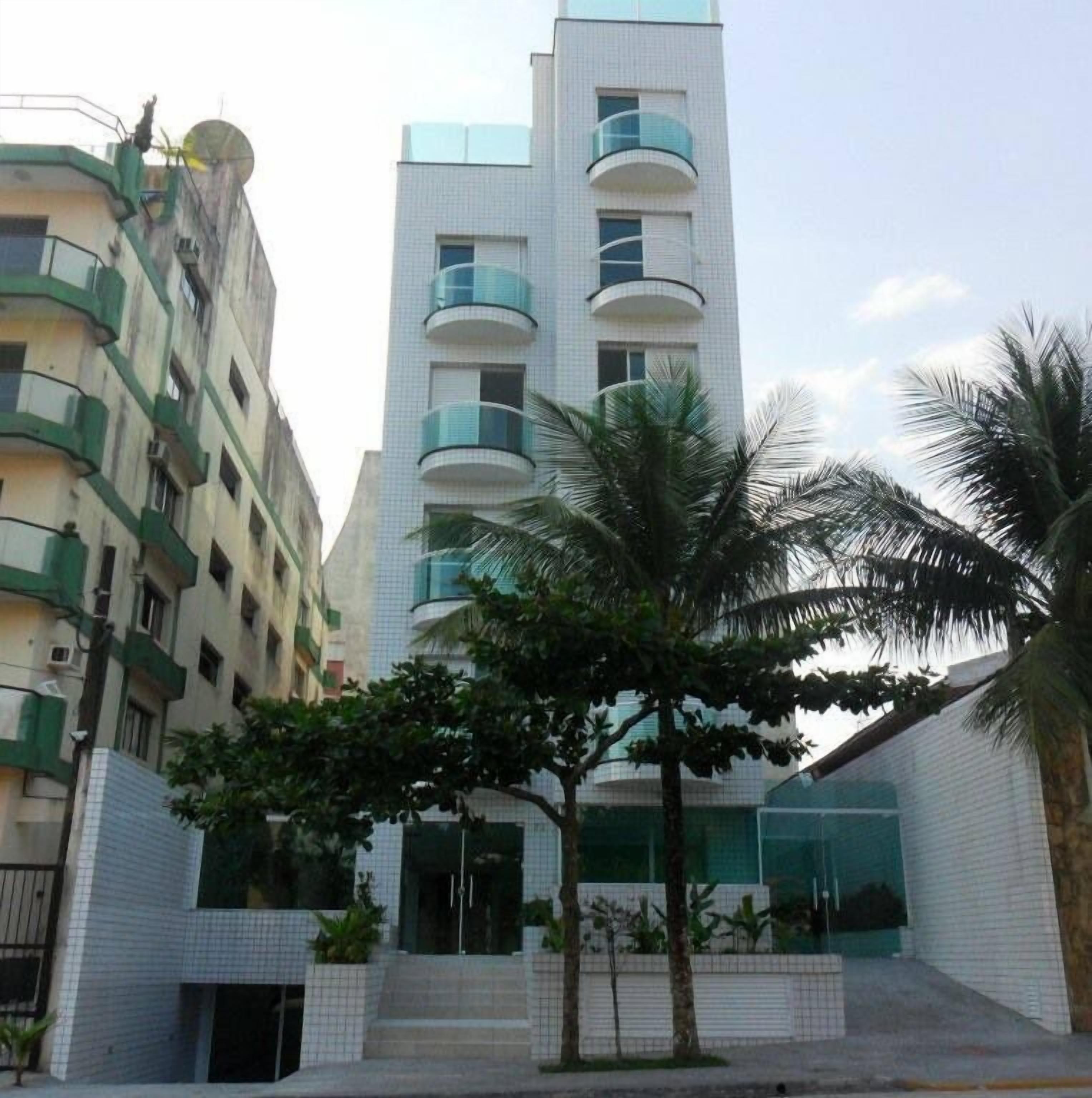 A modern building with multiple floors, balconies, and a gated entrance.