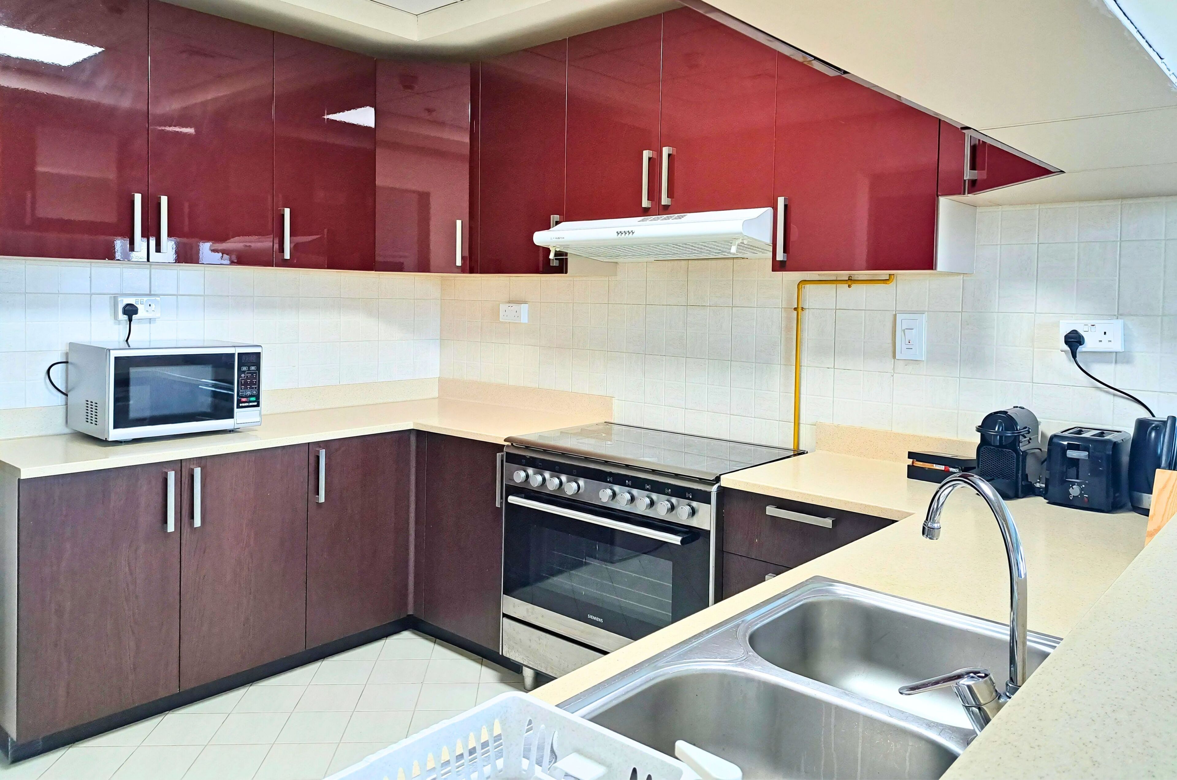 A kitchen with a microwave, oven, sink, and red cabinets.