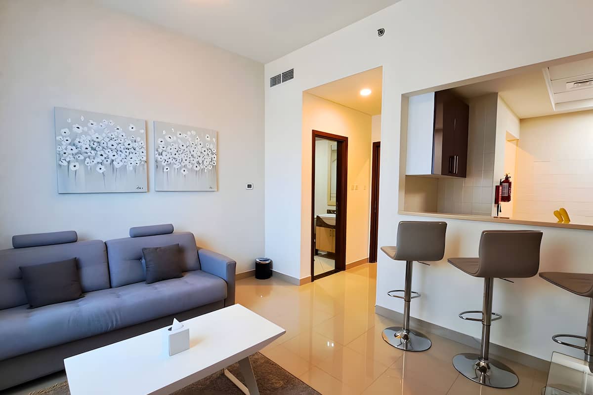 A modern living room with a grey sofa, a white coffee table, and two abstract wall art pieces.