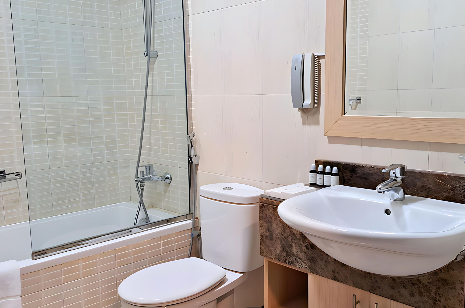 Une salle de bain avec une douche à parois de verre, des toilettes, un lavabo avec un plan de toilette en marbre et un miroir.