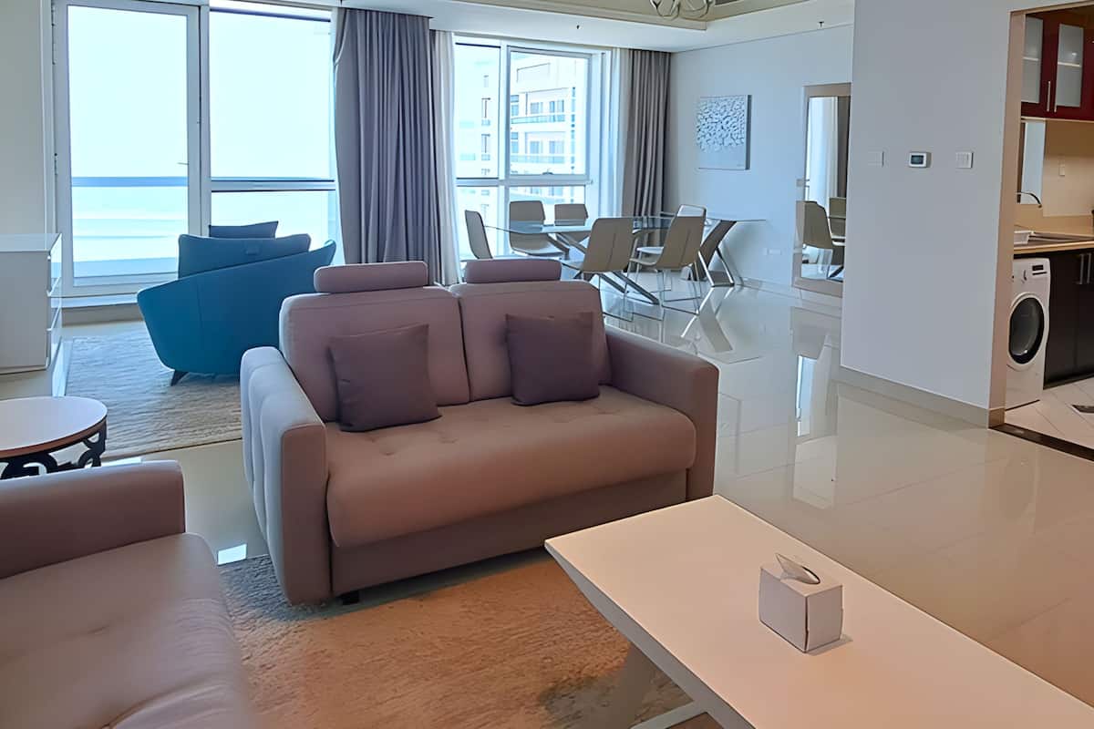 A modern living room with a sofa, a coffee table, and a dining area with chairs and a glass table.