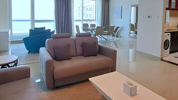Un salon moderne comprenant un canapé, une table basse et un coin repas avec des chaises et une table en verre.