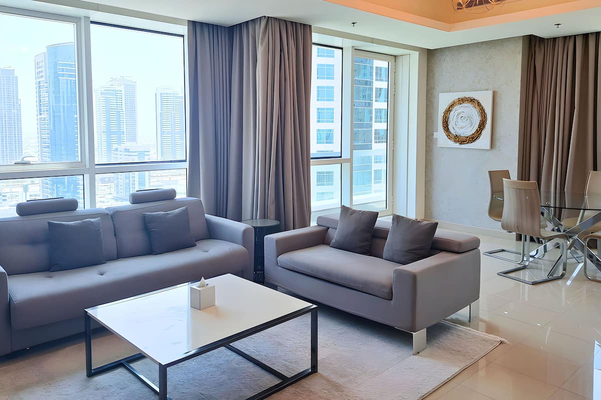 A modern living room with two sofas, a coffee table, and a dining area with chairs and a glass table.