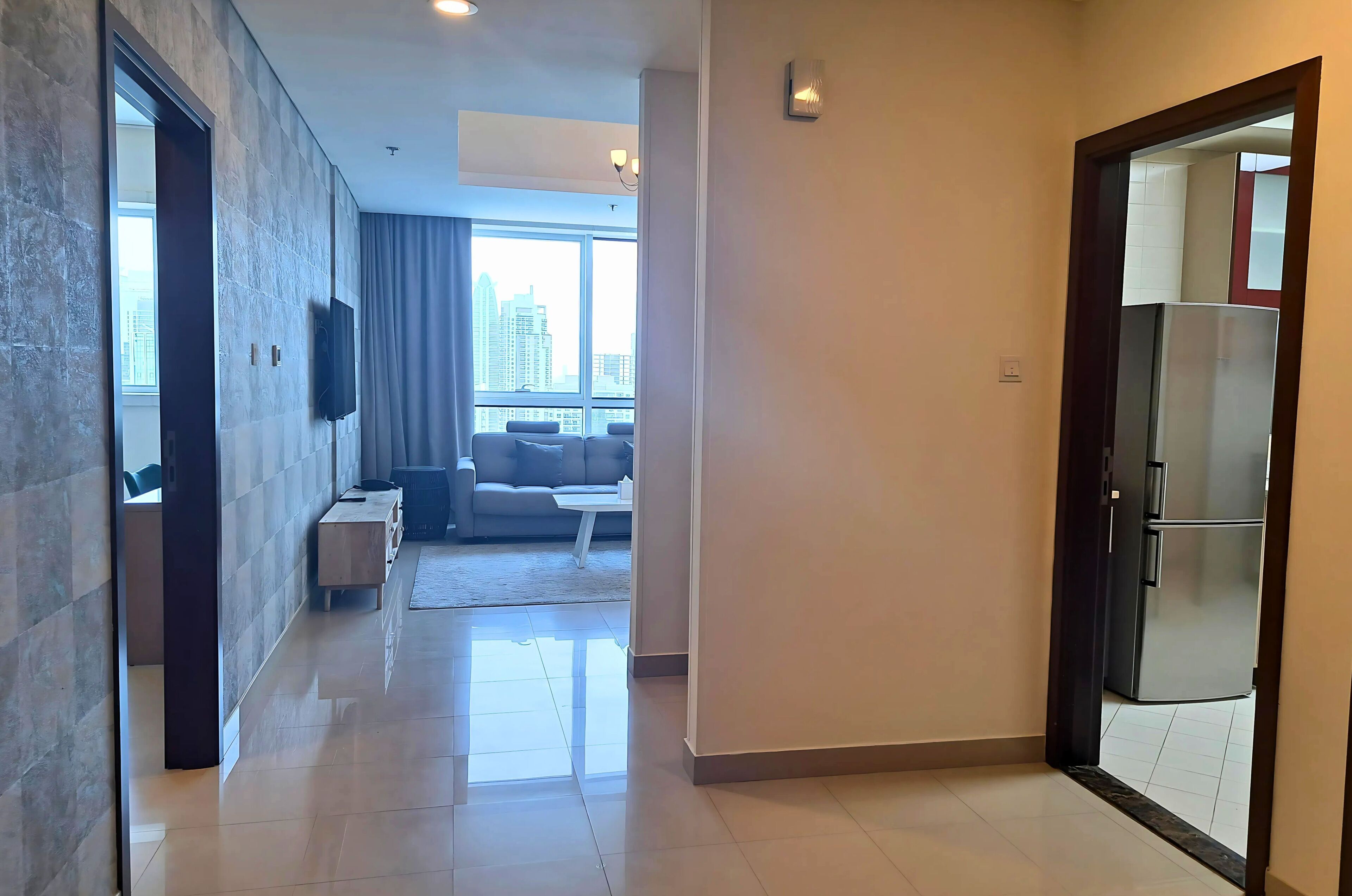 Quarto de hotel moderno com uma janela grande, televisão de tela plana, sofá e área de jantar.