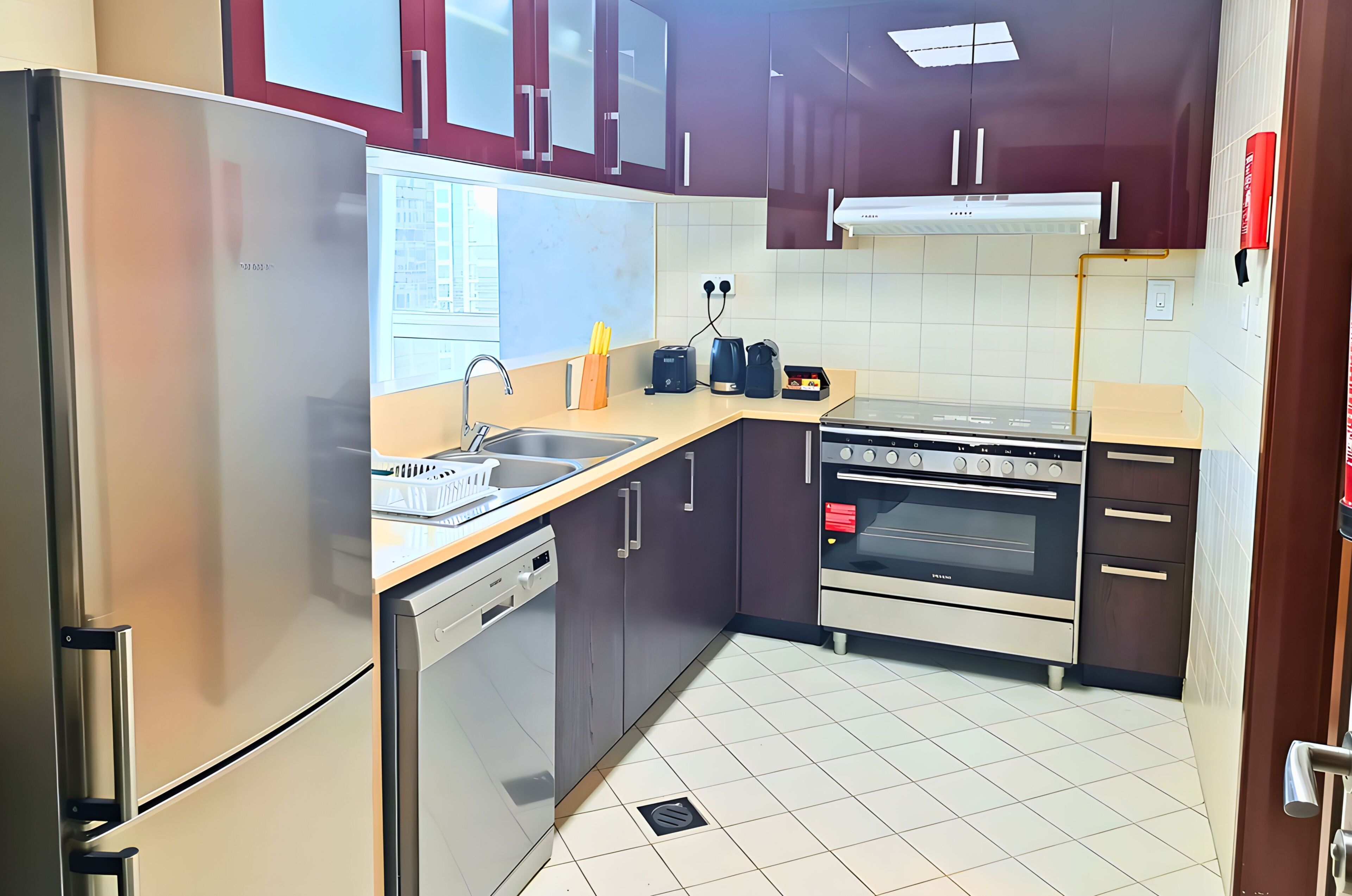 Een keuken met een roestvrijstalen koelkast, een vaatwasser, een dubbele oven en een spoelbak met een kraan.