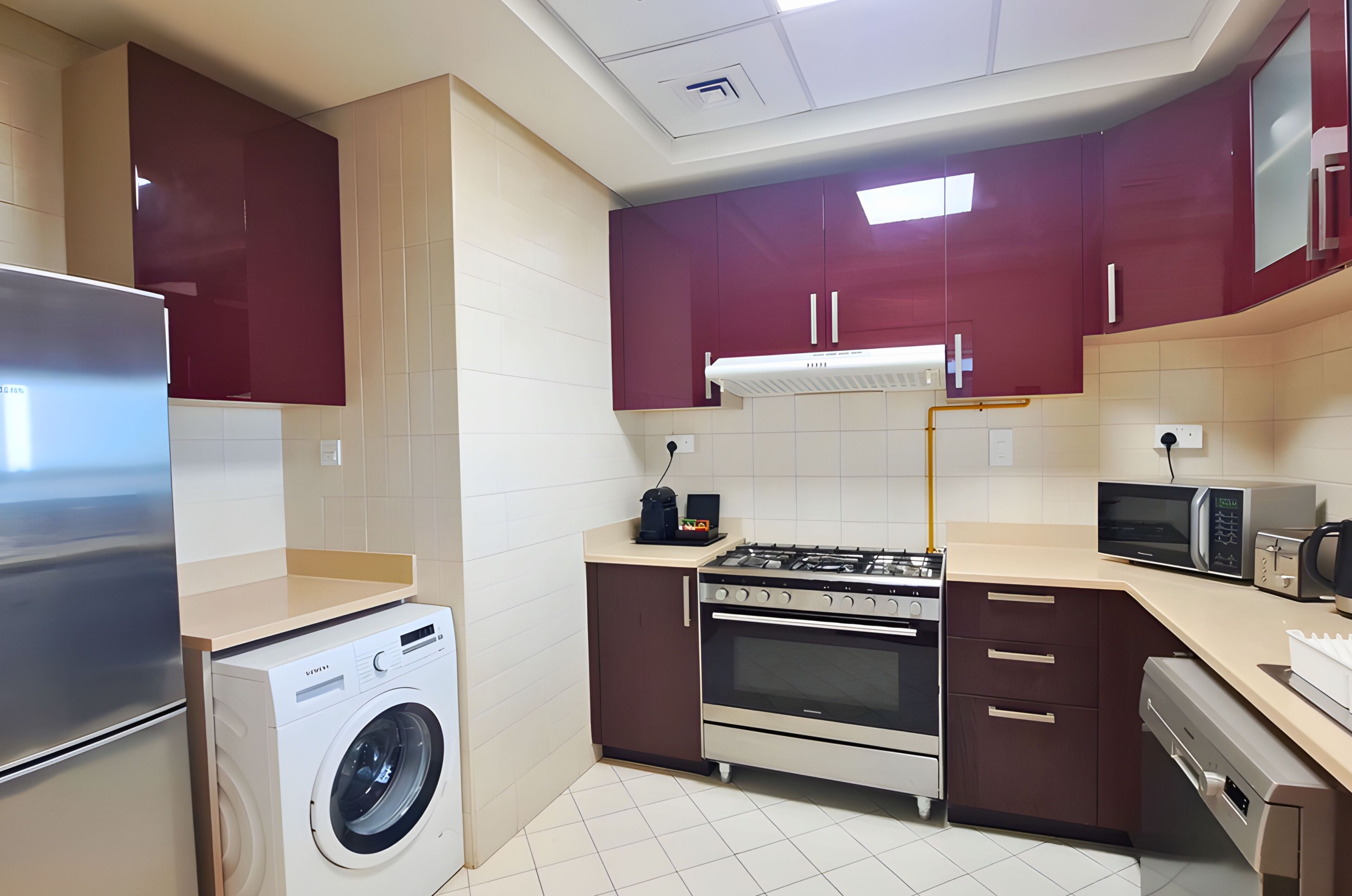 Une cuisine compacte équipée d’un lave-linge, d’une cuisinière, d’un four, d’un four à micro-ondes et d’une machine à café.