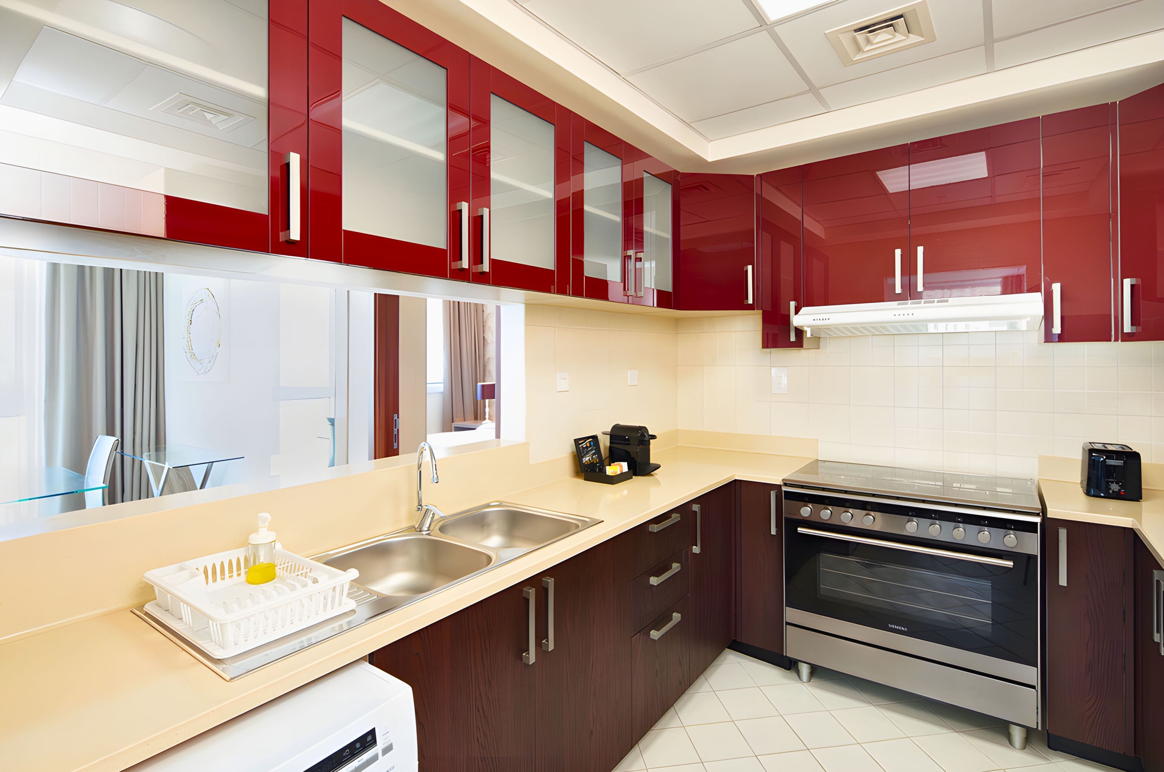 A modern kitchen with red cabinets, stainless steel appliances, and a glass backsplash.