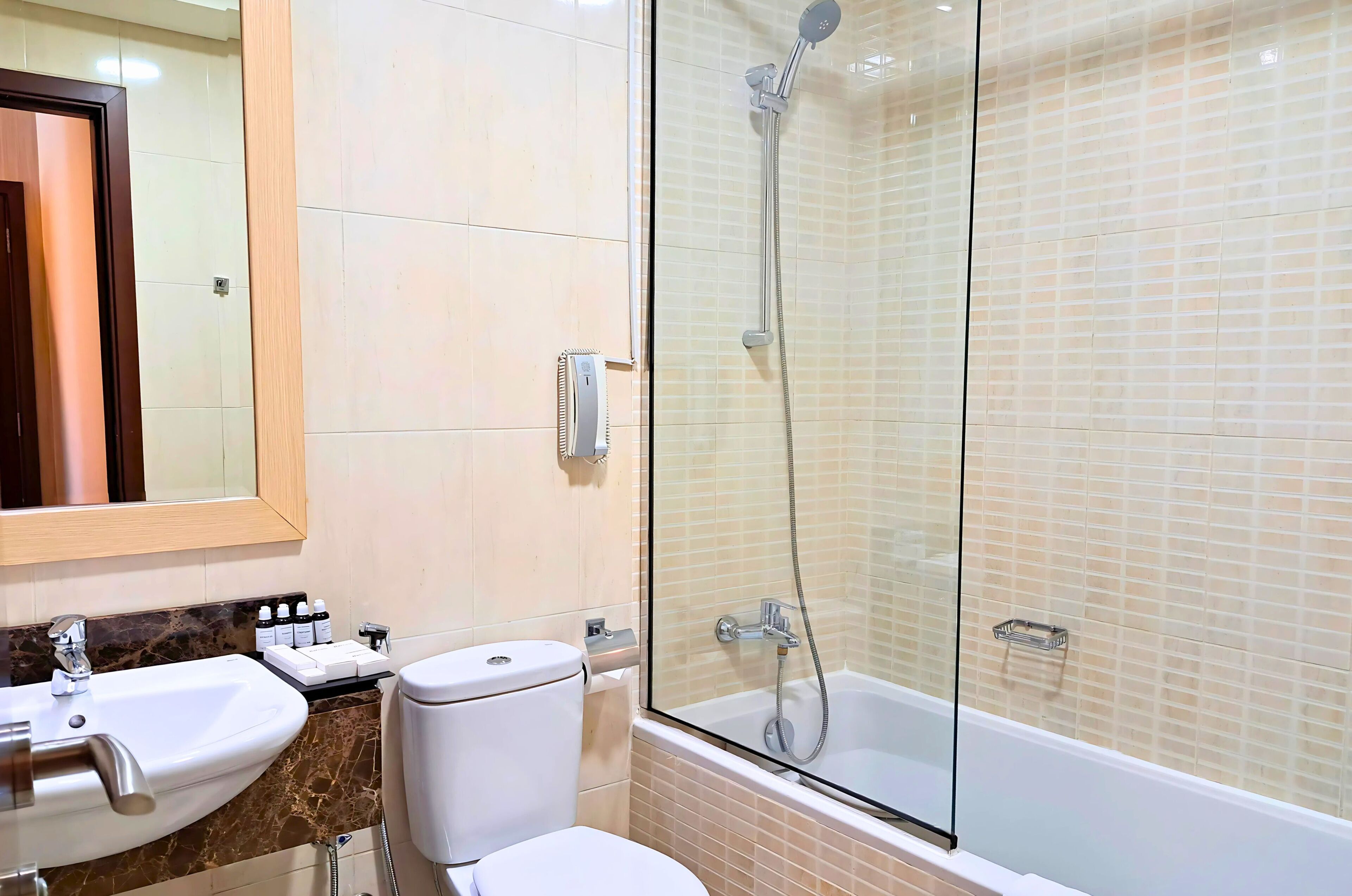 Un baño con ducha acristalada, lavabo e inodoro.