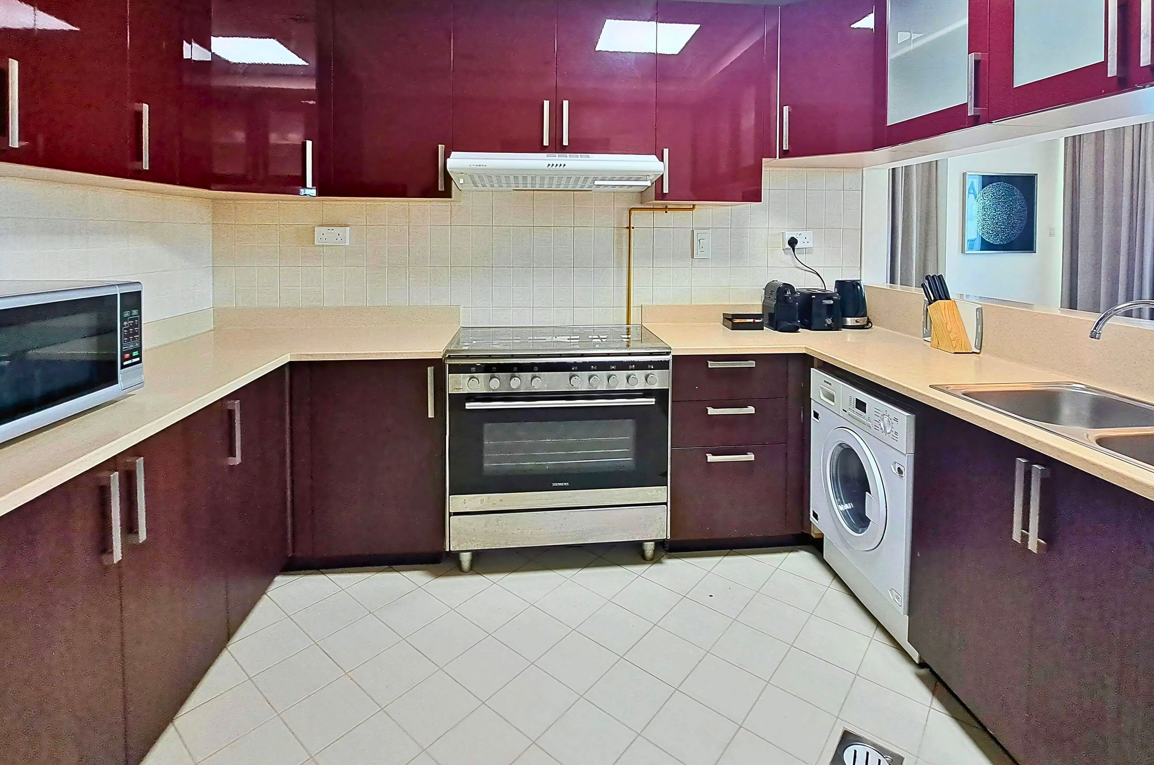 Une cuisine compacte équipée d’un four à micro-ondes, d’une cuisinière, d’un four et d’un lave-linge.