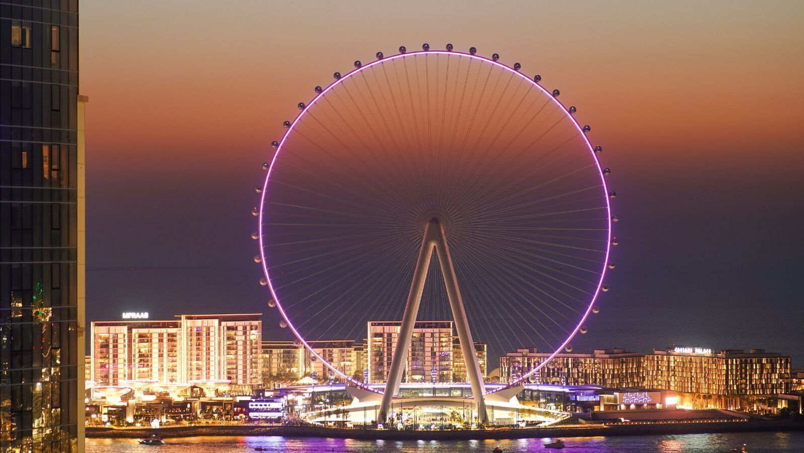 A large Ferris wheel with a modern bridge structure in the foreground.