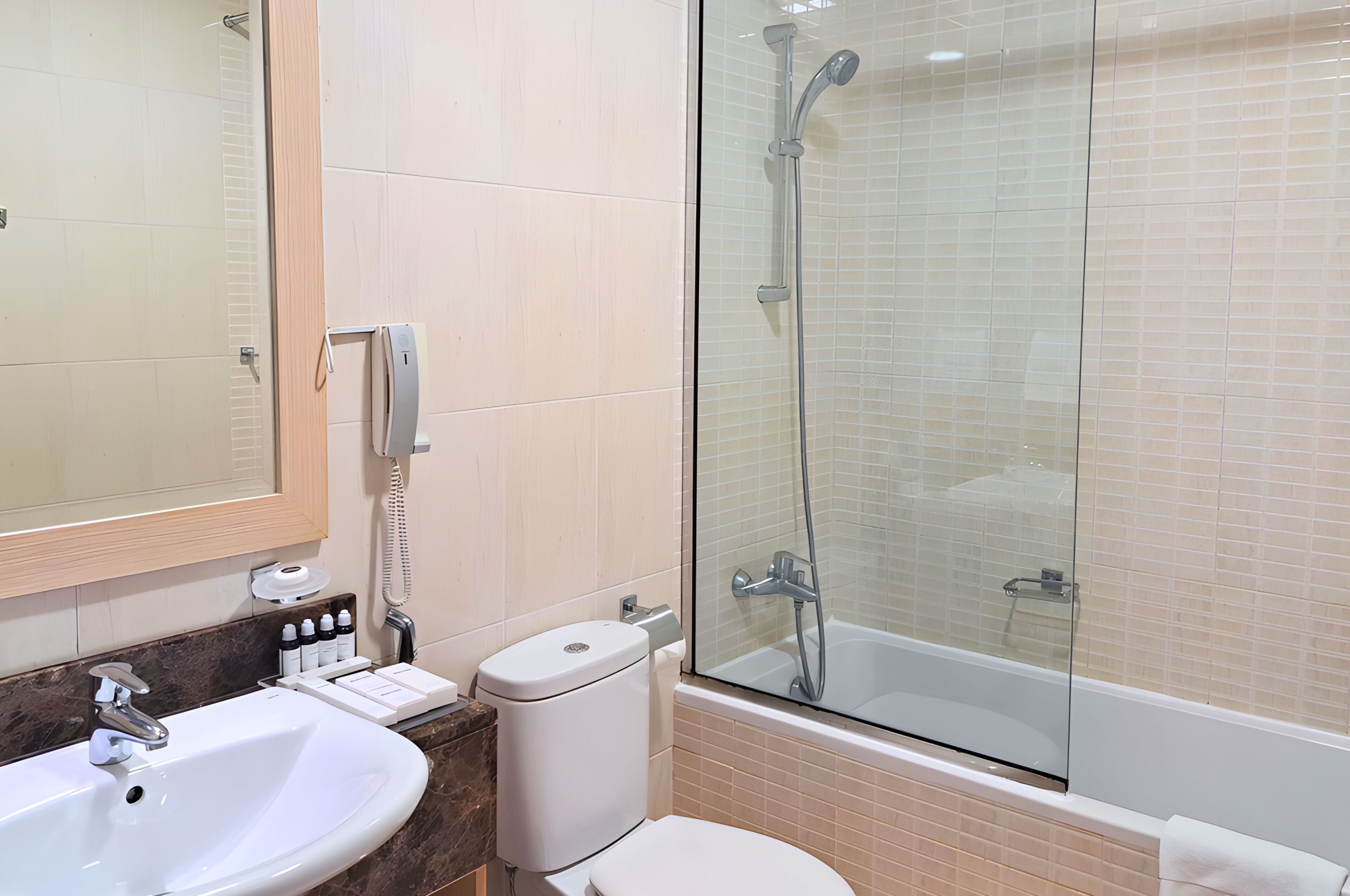 Un baño con lavamanos, inodoro y cabina de ducha acristalada.